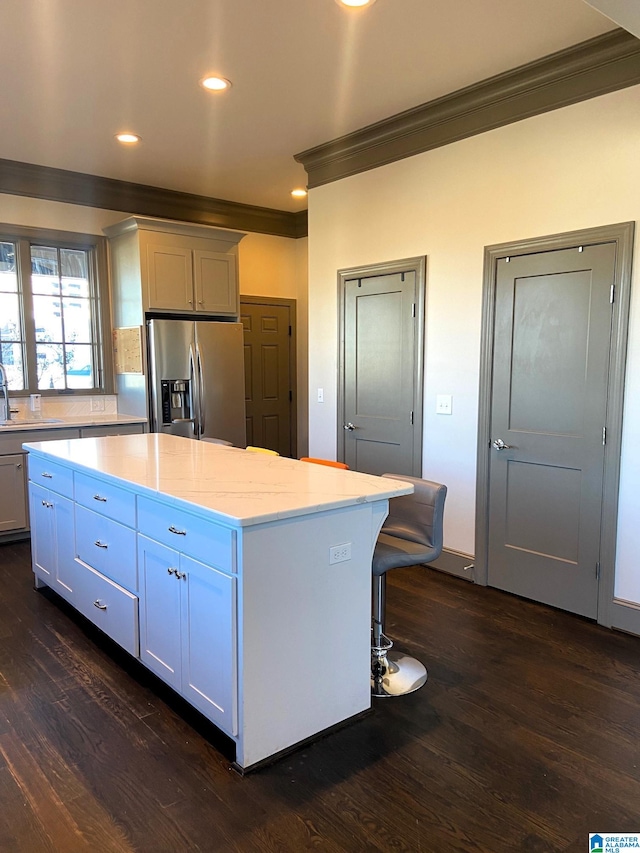 kitchen featuring crown molding, stainless steel fridge with ice dispenser, a center island, and dark wood finished floors