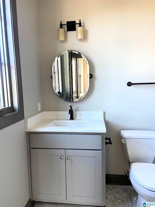 half bath with vanity, baseboards, and toilet