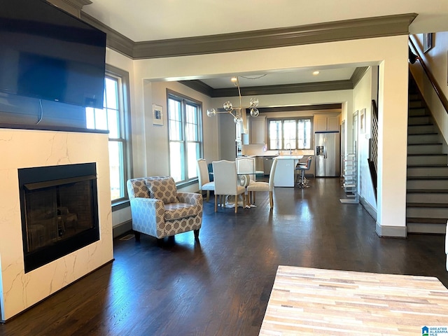 living area with crown molding, a fireplace, stairs, and dark wood-style floors