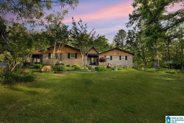 ranch-style home featuring a lawn and brick siding