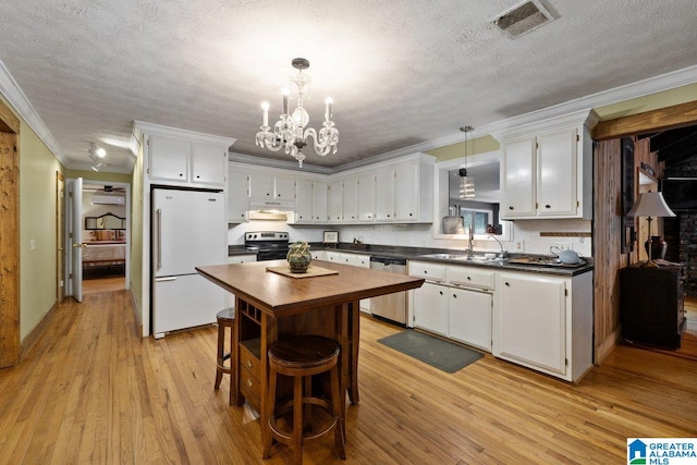 kitchen with crown molding, a textured ceiling, a chandelier, light wood finished floors, and stainless steel appliances