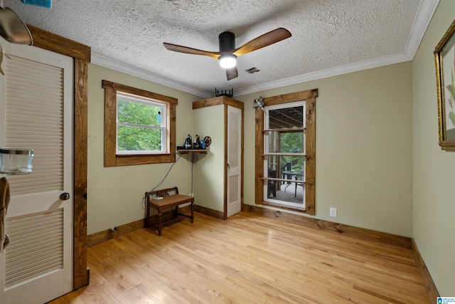 bedroom featuring baseboards, ornamental molding, a textured ceiling, and wood finished floors