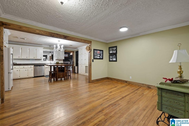 living room with a textured ceiling, an inviting chandelier, ornamental molding, and light wood-style flooring
