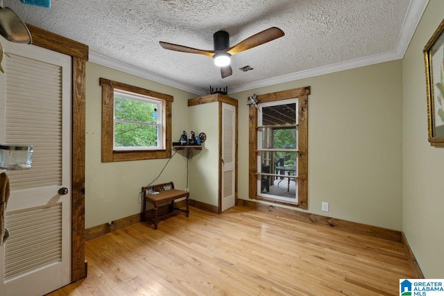interior space with crown molding, a textured ceiling, baseboards, and wood finished floors