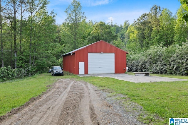 detached garage with dirt driveway and a wooded view