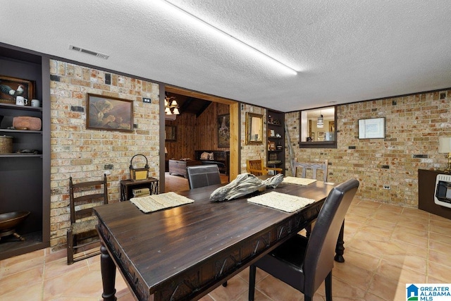 dining room with wooden walls, a textured ceiling, brick wall, heating unit, and visible vents