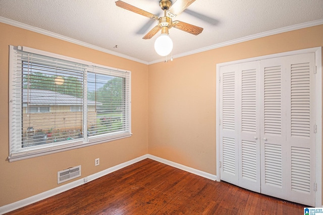 unfurnished bedroom with visible vents, crown molding, a closet, baseboards, and dark wood-style floors