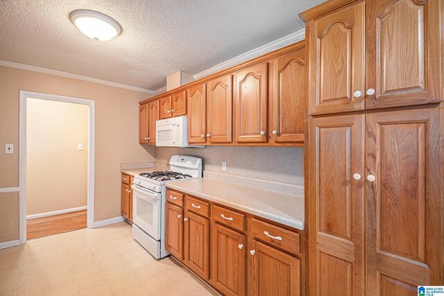 kitchen with crown molding, white appliances, light countertops, a textured ceiling, and light floors