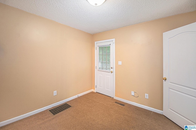 empty room featuring light colored carpet, baseboards, visible vents, and a textured ceiling