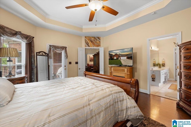 bedroom with wood finished floors, ornamental molding, ensuite bathroom, a ceiling fan, and baseboards