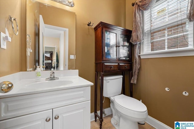 bathroom with toilet, tile patterned floors, baseboards, and vanity