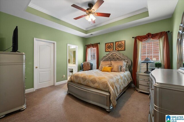 bedroom featuring ornamental molding, a raised ceiling, carpet, ensuite bath, and baseboards