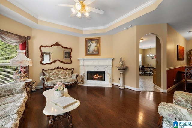 living room featuring ceiling fan, arched walkways, wood finished floors, crown molding, and a high end fireplace