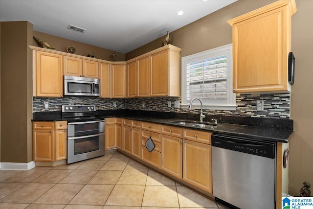 kitchen featuring stainless steel appliances, a sink, light brown cabinetry, and light tile patterned floors