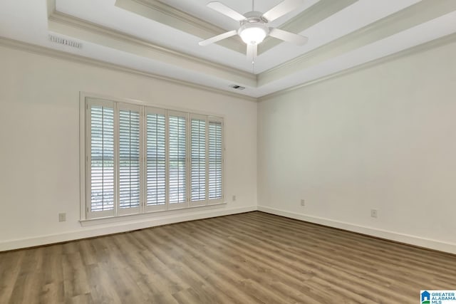 unfurnished room with crown molding, visible vents, wood finished floors, and a raised ceiling