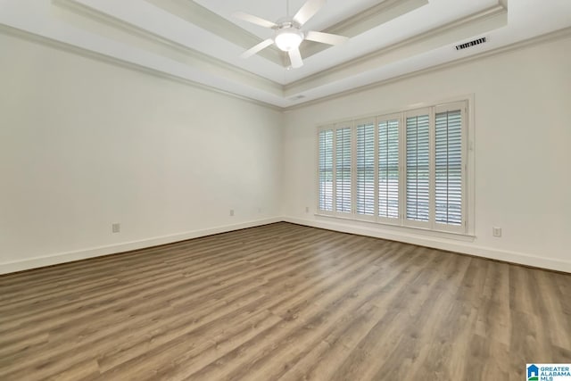 spare room with crown molding, a ceiling fan, visible vents, and a raised ceiling