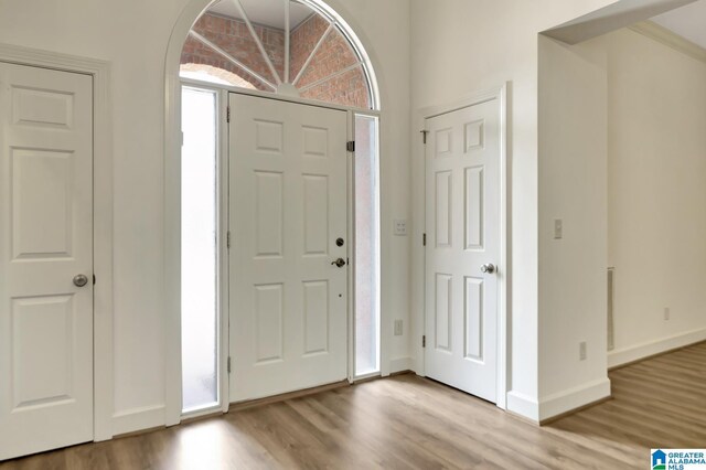 foyer entrance featuring baseboards, arched walkways, and wood finished floors