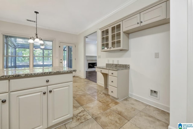 kitchen with visible vents, glass insert cabinets, baseboards, light stone counters, and decorative light fixtures