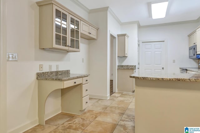 kitchen with cream cabinets, crown molding, light stone counters, stainless steel microwave, and glass insert cabinets