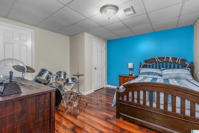 bedroom with baseboards, visible vents, a paneled ceiling, and wood finished floors