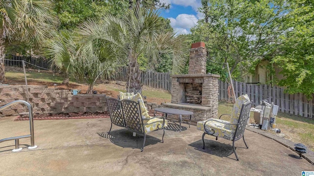 view of patio / terrace featuring an outdoor stone fireplace and a fenced backyard