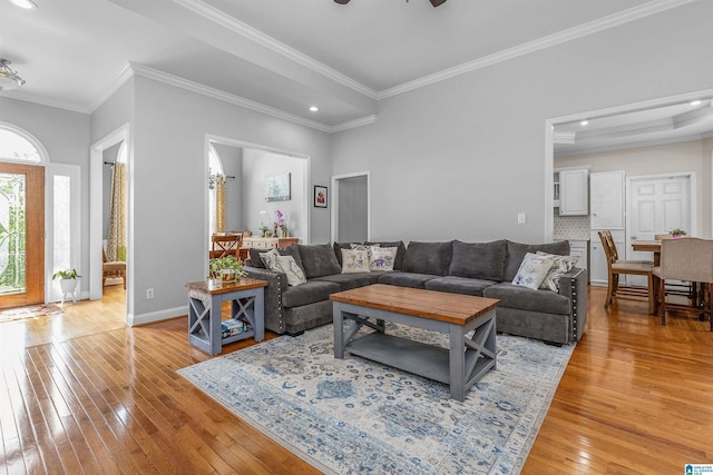 living area with light wood-style floors, a ceiling fan, crown molding, and recessed lighting