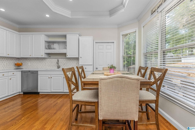 dining area with recessed lighting, a raised ceiling, light wood-style flooring, and crown molding