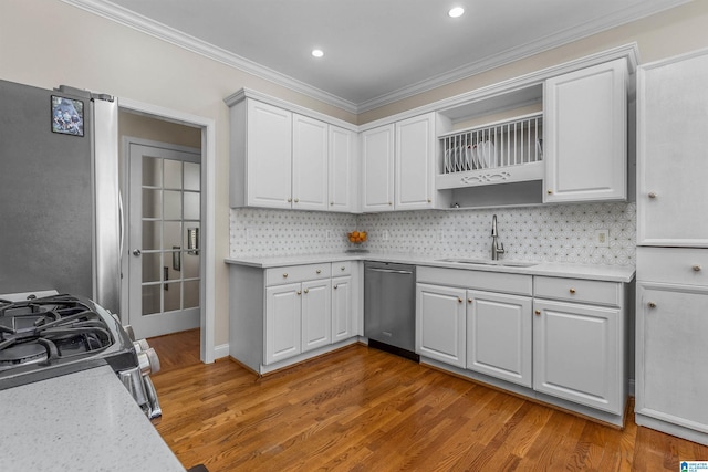 kitchen featuring a sink, light countertops, light wood-style flooring, stainless steel appliances, and decorative backsplash