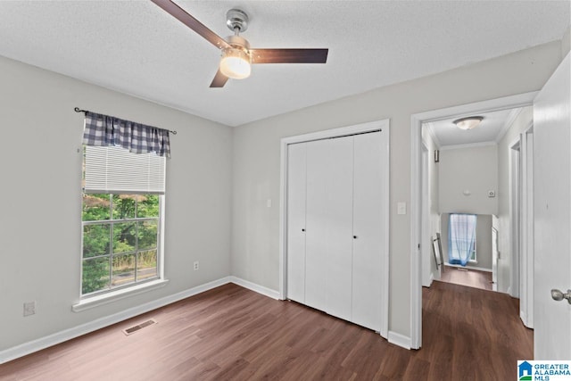 unfurnished bedroom with visible vents, a closet, wood finished floors, baseboards, and a ceiling fan