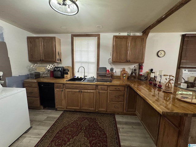 kitchen with a sink, black dishwasher, a peninsula, washer / clothes dryer, and light wood-type flooring