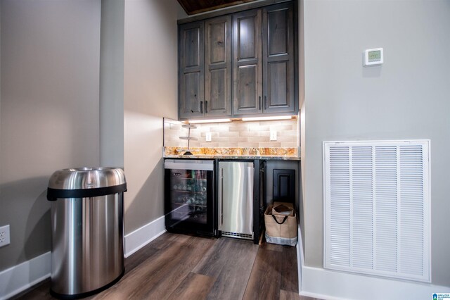 bar with freestanding refrigerator, beverage cooler, baseboards, a bar, and dark wood finished floors