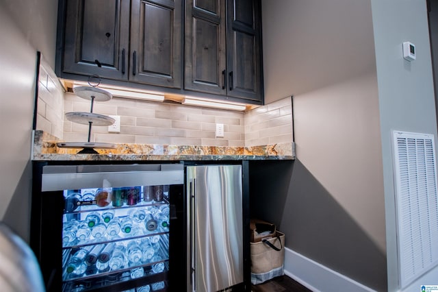 bar with beverage cooler, a heating unit, freestanding refrigerator, baseboards, and backsplash