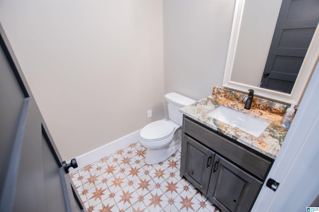 half bathroom featuring toilet, tile patterned floors, baseboards, and vanity