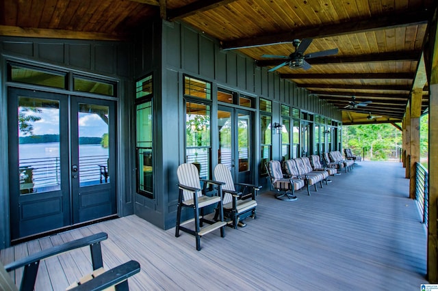 deck with a water view, ceiling fan, and french doors