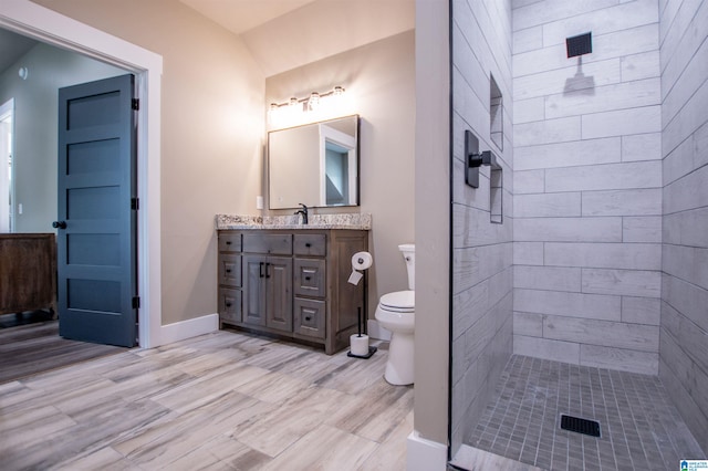 full bathroom featuring vanity, baseboards, toilet, and tiled shower