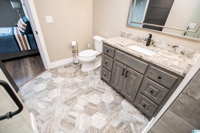 bathroom with toilet, baseboards, and vanity