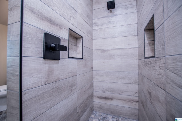 full bathroom featuring a tile shower and toilet