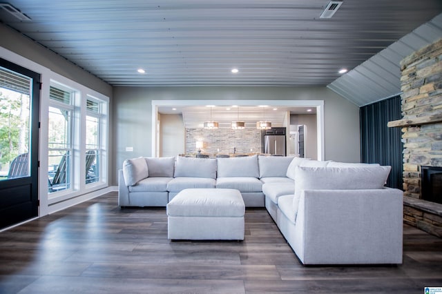 living area with visible vents, wood finished floors, a stone fireplace, recessed lighting, and wooden ceiling