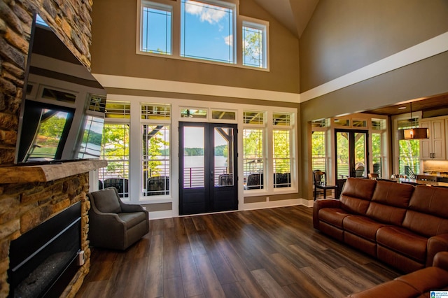 living room featuring french doors, a fireplace, wood finished floors, high vaulted ceiling, and baseboards