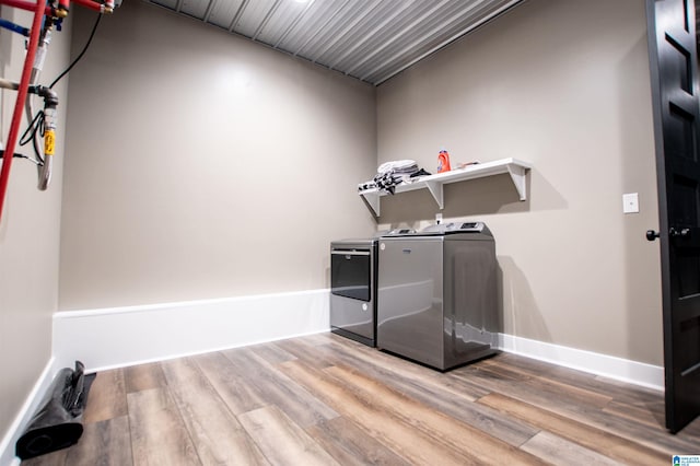 washroom with washing machine and clothes dryer, laundry area, baseboards, and wood finished floors