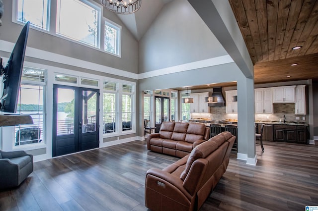 living area with french doors, a high ceiling, dark wood-style floors, and wooden ceiling