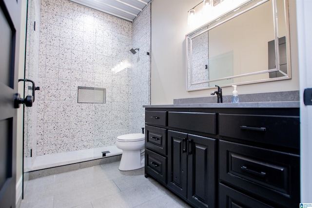 bathroom with vanity, tile patterned floors, a tile shower, and toilet