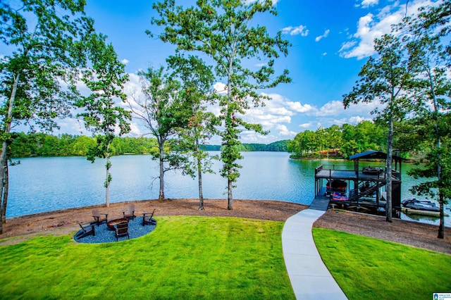 water view with boat lift, a dock, and a fire pit