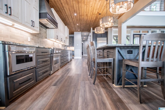 kitchen featuring white cabinets, oven, a chandelier, wooden ceiling, and custom exhaust hood