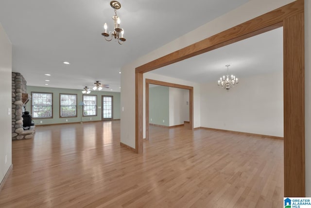 unfurnished living room with recessed lighting, baseboards, ceiling fan with notable chandelier, and light wood-style floors