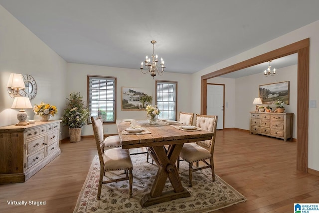 dining space featuring an inviting chandelier, baseboards, and light wood-style flooring