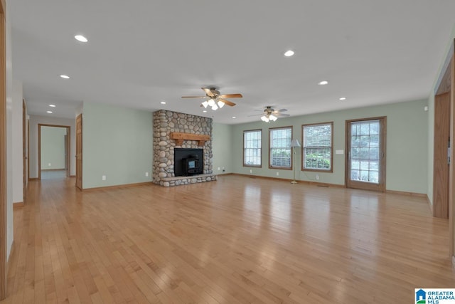 unfurnished living room featuring plenty of natural light, a ceiling fan, light wood finished floors, and a fireplace