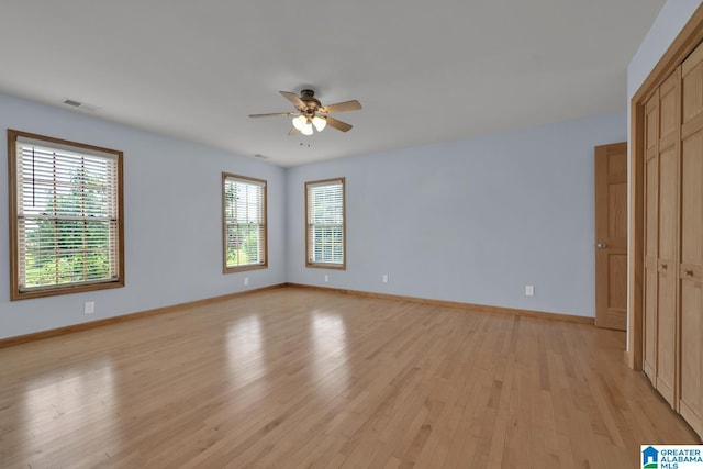 empty room with baseboards, ceiling fan, light wood-style flooring, and visible vents