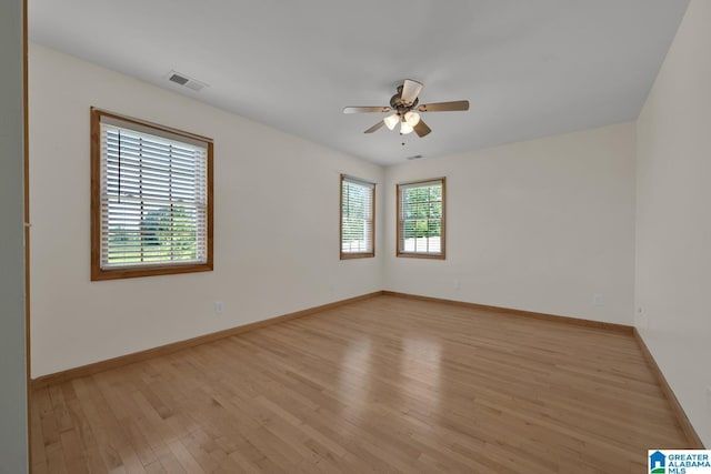 spare room featuring baseboards, ceiling fan, visible vents, and light wood-style flooring