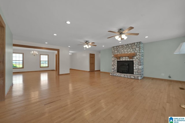 unfurnished living room featuring light wood finished floors, a fireplace, ceiling fan with notable chandelier, and recessed lighting
